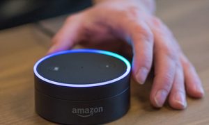Una mano tomando un dispositivo Alexa, para aprender cómo configurar Alexa