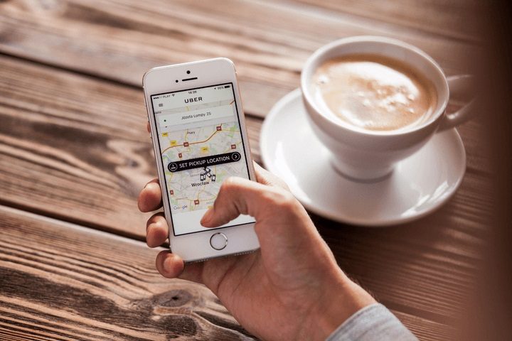 Una persona revisa un mapa de Uber en su teléfono celular mientras toma un café. Cómo borrar una cuenta de Uber
