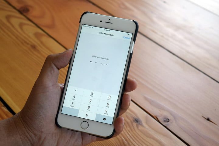 Una persona sostiene un iPhone que tiene una pantalla de ingreso de claves