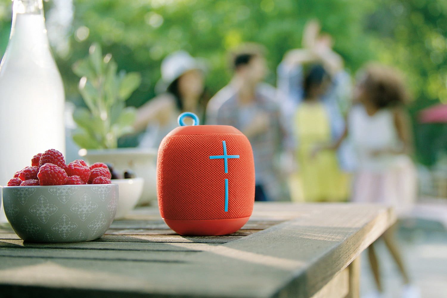 El altavoz Ultimate Ears Wonderboom de color rojo, uno de los mejores productos electrónicos por menos de $100 dólares, está ubicado en la esquina de una mesa de un campamento al aire libre.