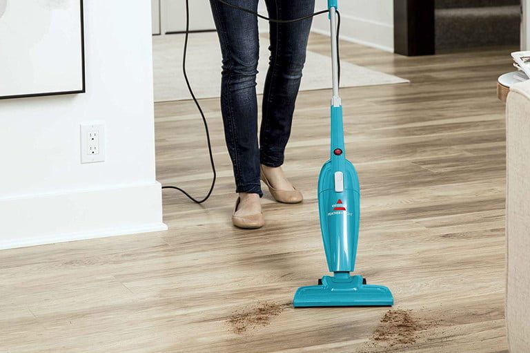 Una mujer manipula la Featherweight de Bissell, una de las mejores aspiradoras livanas, en una sala de estar.