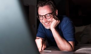 Joven riendo frente a su computadora portátil después de activar el Modo oscuro en Windows 10