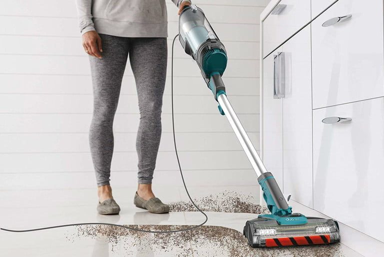 Una mujer recoge el polvo de su cocina con la Shark Apex UpLight, una de las mejores aspiradoras livianas.