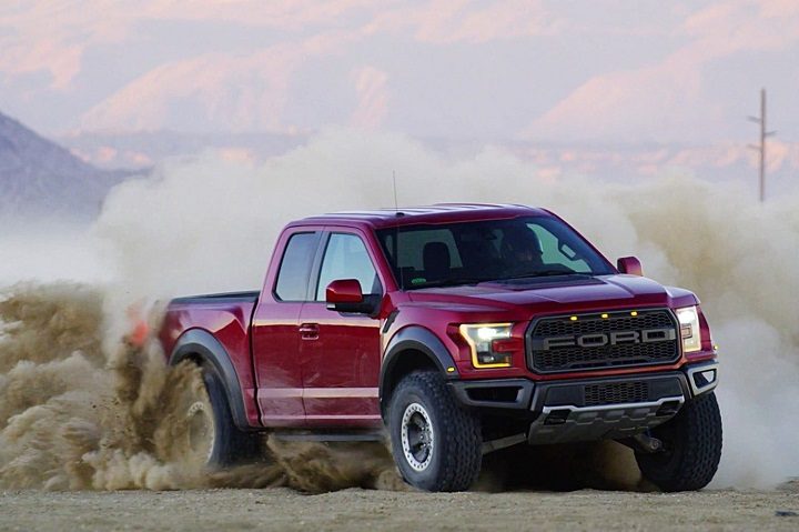 Una Ford F-150 de color rojo avanza a gran velocidad levantando arena. Comparamos la Tesla Cybertruck vs. Ford F-150