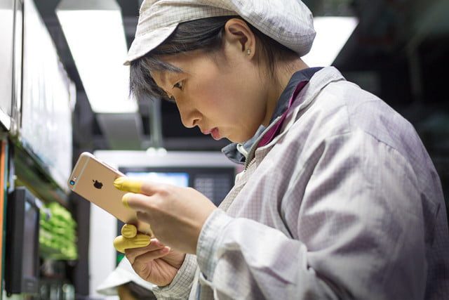 Una mujer sostienen un iPhone en sus manos en la línea de producción de teléfonos.