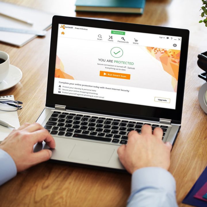 Una persona escribe en su computadora mientras en la pantalla aparece un mensaje de protección de Avast, uno de los mejores antivirus para PC.