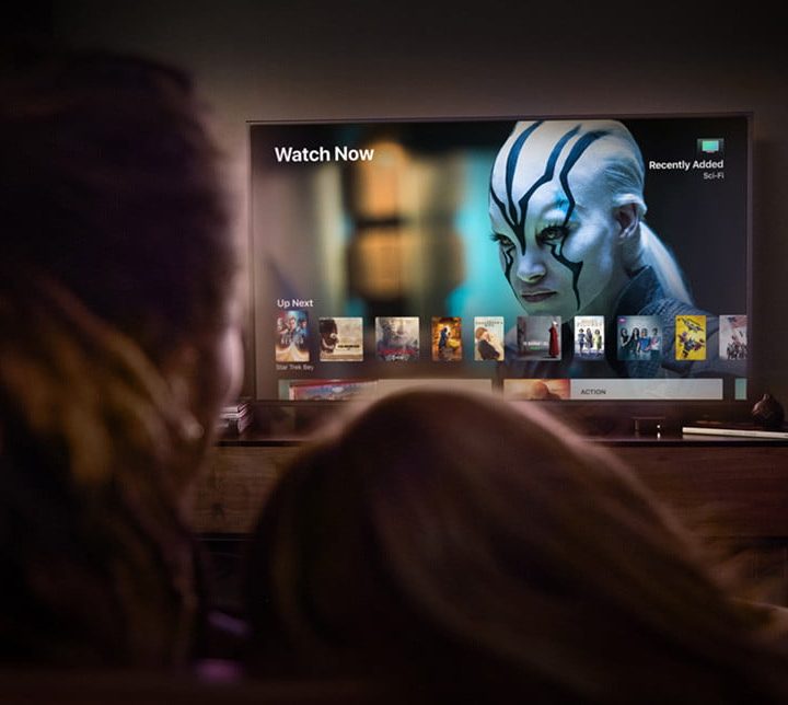 Una pareja sentada en su sofá mira el televisor. Comparamos los servicios de streaming Netflix, Hulu y Amazon Prime Video