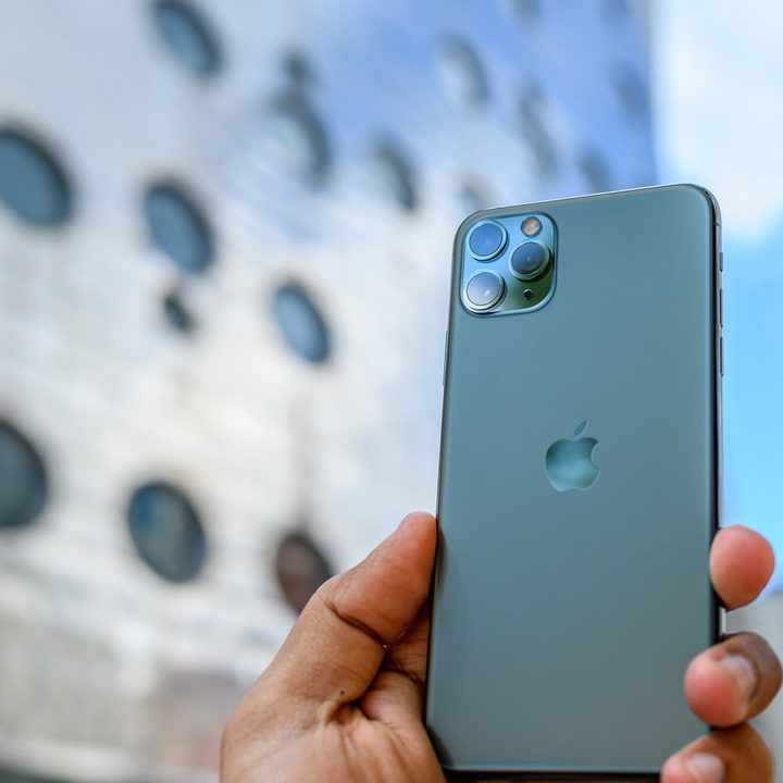 Una persona sostiene un teléfono iPhone 11 Pro Max en la calle. Te explicamos cómo restaurar de fábrica un iPhone