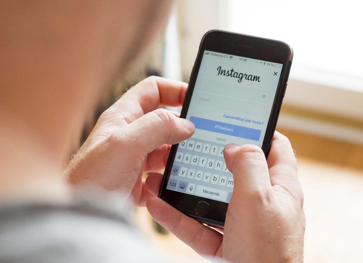 Una persona sosteniendo un celular en sus manos visto desde atras