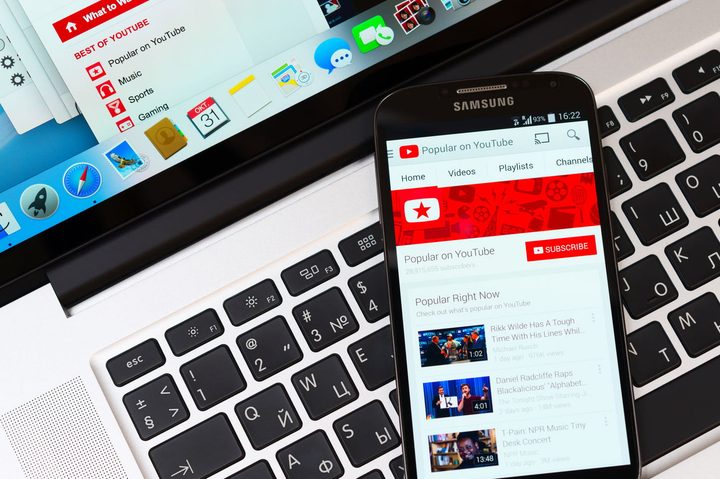 Un teléfono inteligente con la app de Youtube abierta sobre un teclado de una laptop