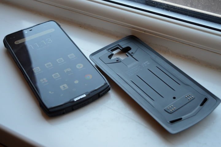 Un teléfono negro sobre una mesa con un tapa negra del mismo tamaño a lado