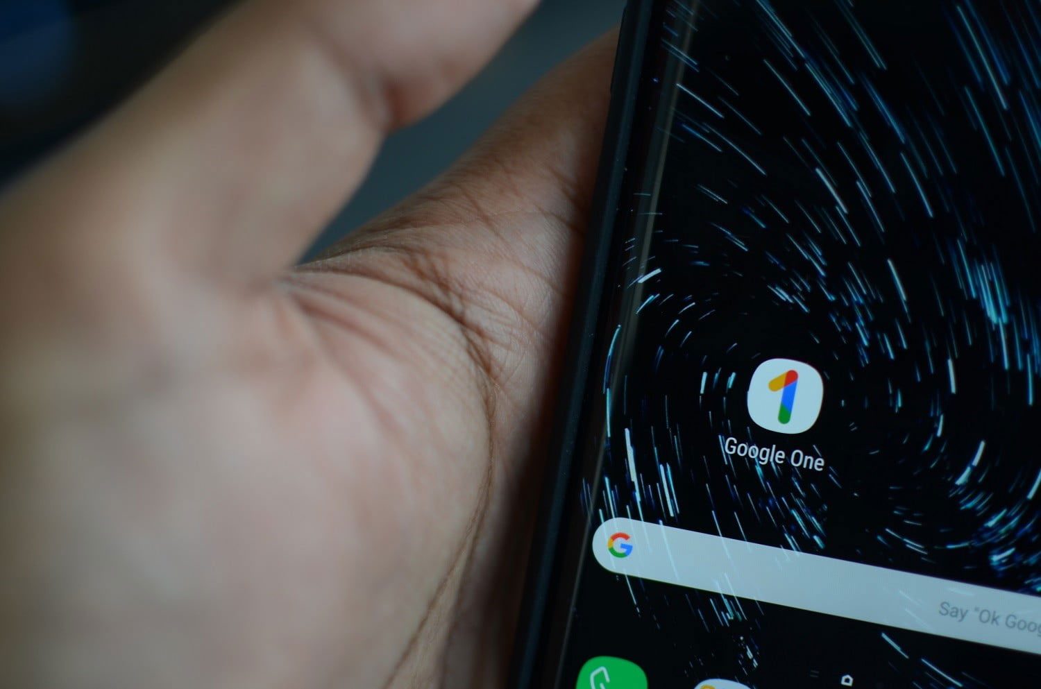 Una persona sostiene un teléfono que en la pantalla muestra el icono de Google One