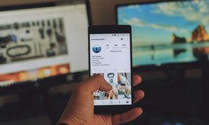 Una persona con su teléfono celular con la aplicación de Instagram abierta apunta a su televisor