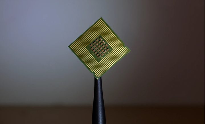 Un chip de computadora es sostenido con un pinza. Comparamos los procesadores i5 y i7