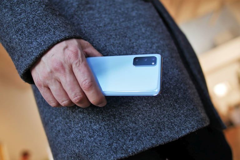 persona agarrando con la mano un Galaxy S20 color blanco
