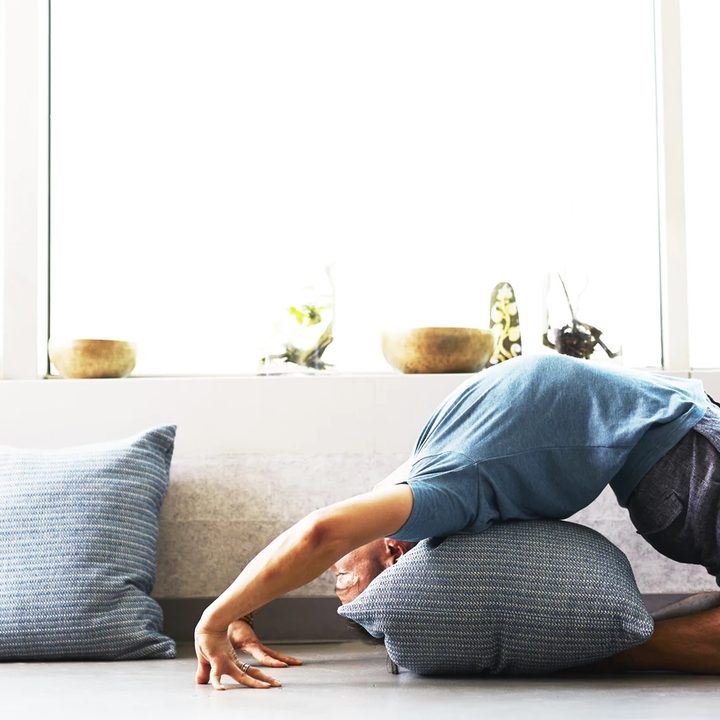 Una persona practica yoga en la sala de su casa con una de las mejores aplicaciones para meditar