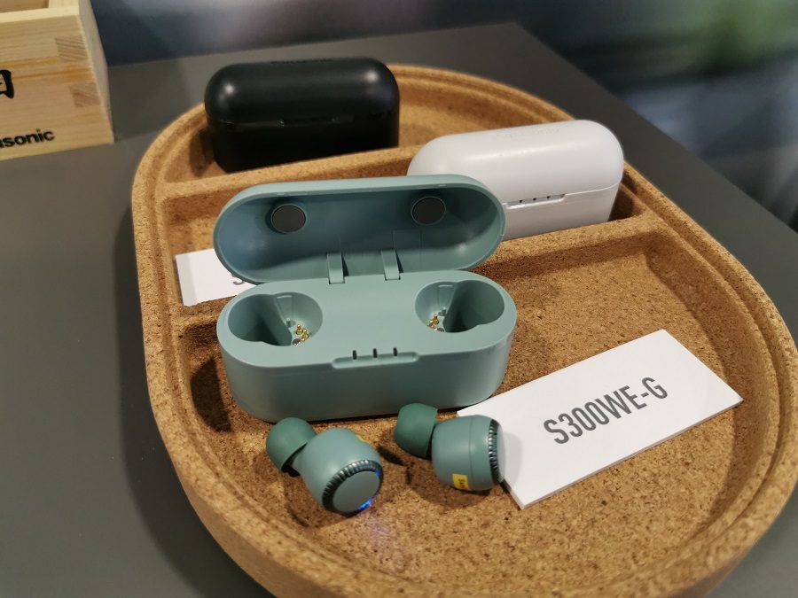 Tres pares de auriculares Panasonic S300W, unos negros, otros grises y otros verdes, sobre una bandeja de corcho