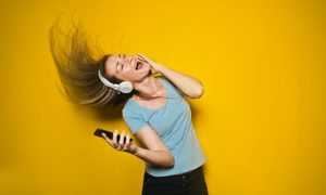 Mujer bailando con auriculares conectados a su celular, porque pudo agregar música al iphone