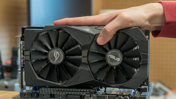 Una mano sosteniendo una tarjeta de video AMD Radeon RX570, una de las mejores tarjetas gráficas para editar video