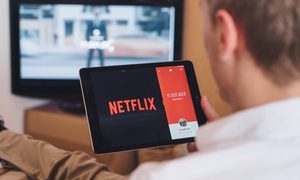 Una persona sostiene una tableta con el logo de Netflix para investigar cuánto cuesta Netflix