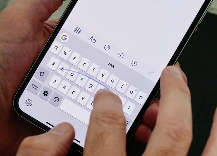 Una persona manipula su iPhone. Cómo usar Swipe Type en iOS 13