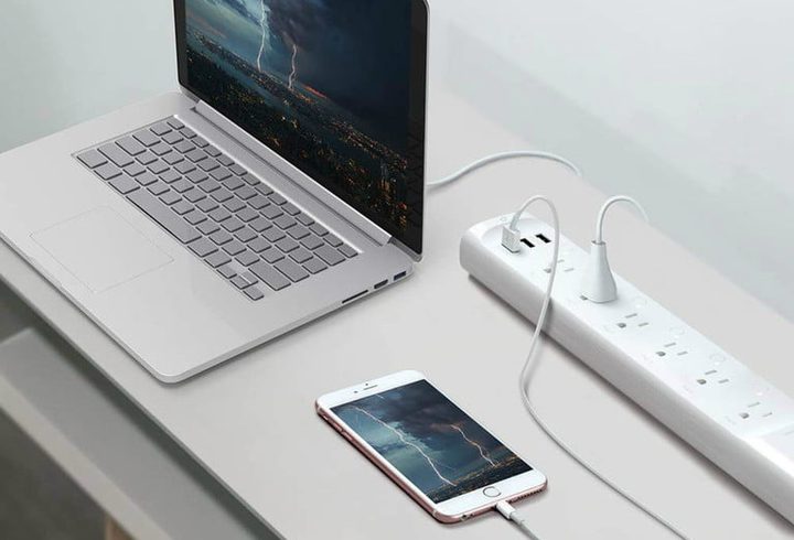 TP-Link Smart Power Strip del cual están conectados una portatil y un celular en una mesa
