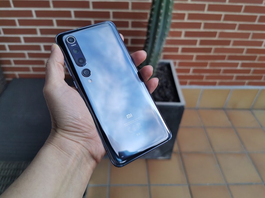 una mano agarra el teléfono xiaomi mi 10 mostrando su parte posterior de color gris con efecto espejode coloro gris con efecto espejo