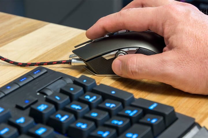 La mano de una persona sobre un mouse y la vista parcial de un teclado