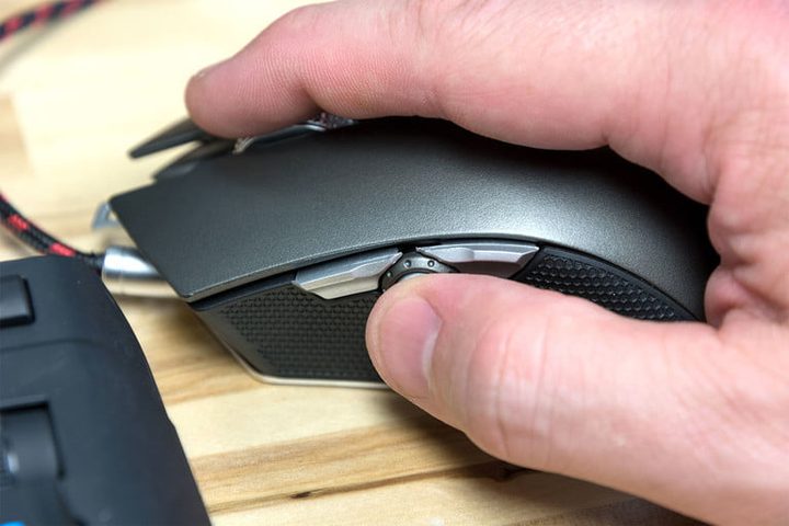 La mano de una persona trabajando con un mouse en una superficie de madera