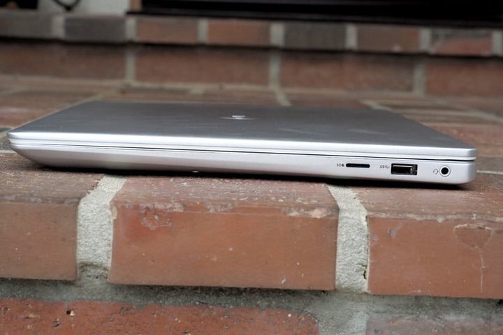 Dell Inspiron 15 7000 cerrada, vista de perfil sobre piso de ladrillos rojos