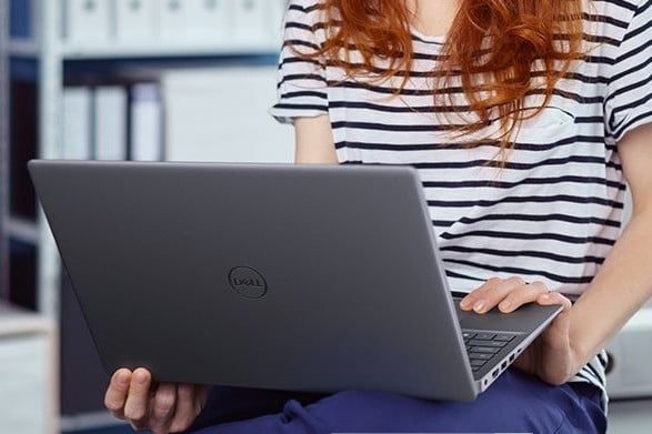 Chica sentada y sobre sus piernas una de las portatiles para hacer el comparativo de Inspiron 15 7000 vs. XPS 15