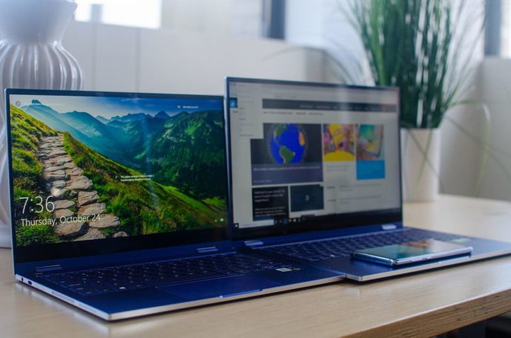 Dos Samsung Galaxy Book Flex sobre una mesa y sobre el pad de una de ellas un celular para carga QI