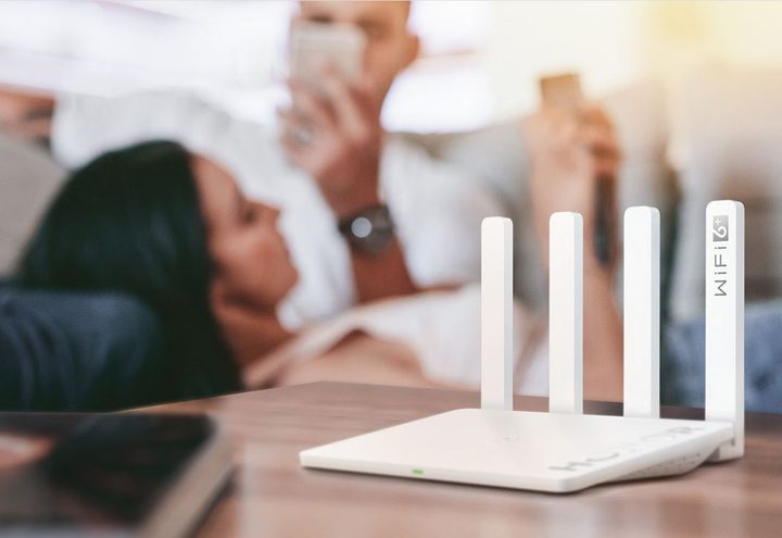 primer plano de Honor Router 3 que está sobre una mesa en un salón con una joven pareja utilizando el teléfono móvil