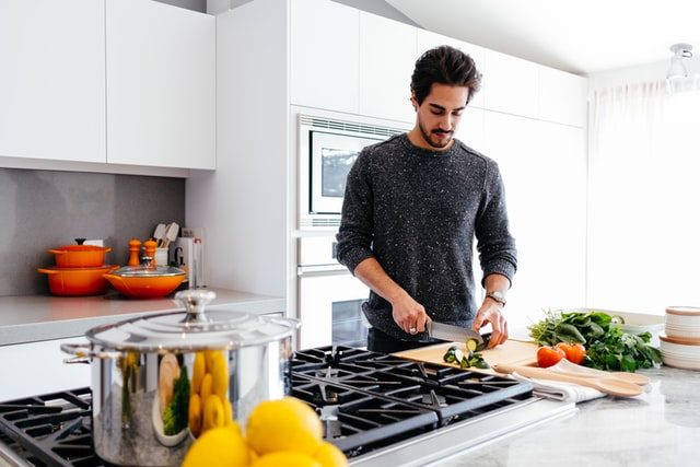 Joven cocinando en una cocina amplia.