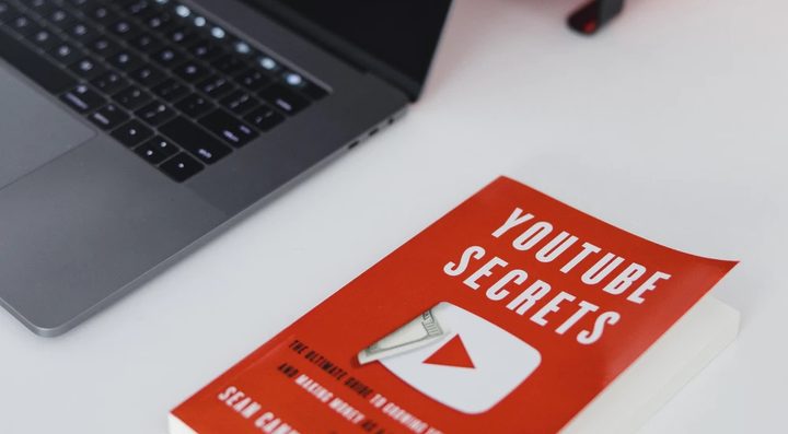 Un libro con secretos de Youtube junto a una laptop