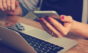 Usuario utilizando su portátil y celular al mismo tiempo.