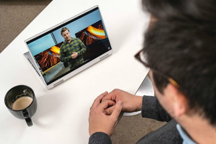 Un hombre observando un video en su Tablet 2-en-1 sobre una mesa y a un lado una taza de café