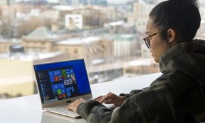 Una mujer usando su laptop para aprender a usar todas las funciones del Explorador de Archivos en Windows 10