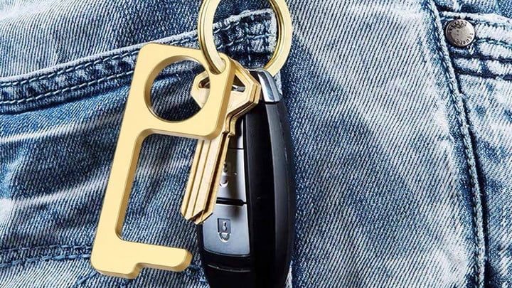 Herramienta de apertura de puertas sin contacto de Forno sujeto en un llavero que está semiguardado en el bolsillo de un pantalón vaquero