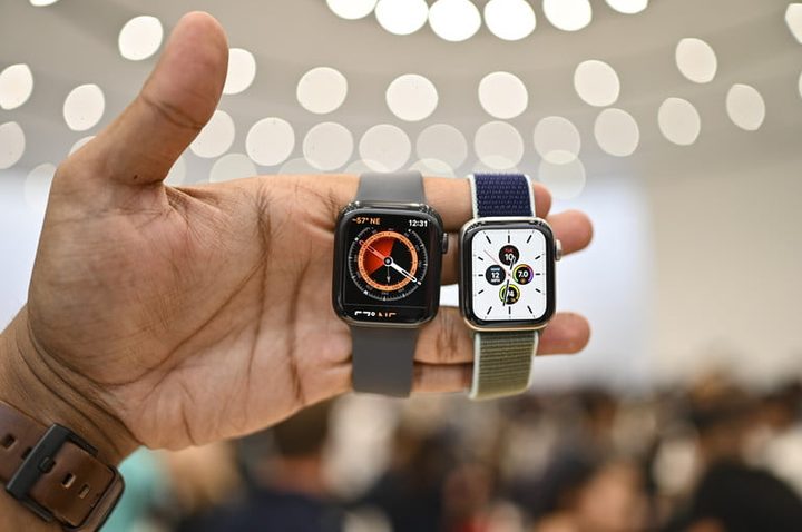 Una mano sostiene un Apple Watch Series 5 y otro reloj inteligente