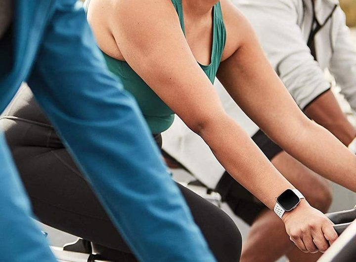 personas en clase de spinning, una de ellas con un reloj fitbit versa 2