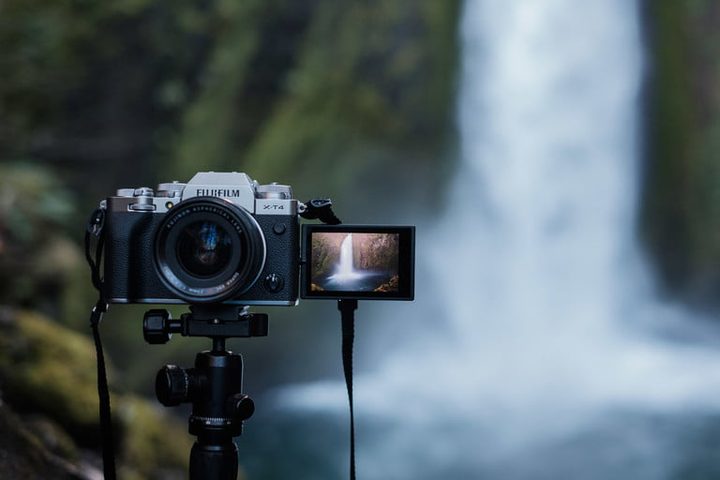 Cámara Fujifilm X-T4, una de las mejores video cámaras para 2020, en un pedestal mostrando la pantalla articulada abierta