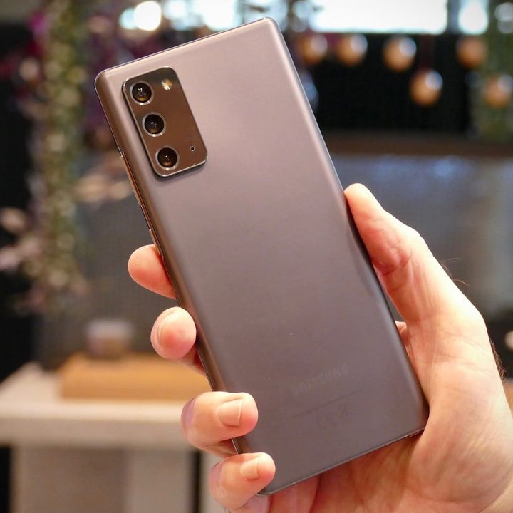 una manor sujeta un galaxy note 20 mostrando la parte trasera de color gris