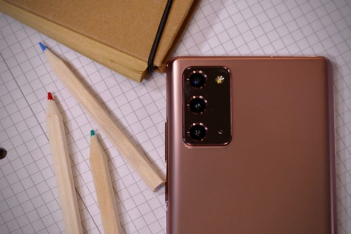 Galaxy Note 20 vs. Galaxy Note 10, este último mostrando su pantalla sobre una superficie de madera, el primero sobre una superficie cuadriculada junto a lapices de colores, mostrando las cámaras de la parte trasera