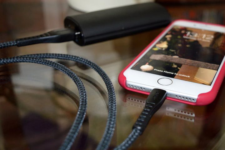 Celular conectado por cable a batería portátil para revisar qué hacer cuando tu iPhone no carga la batería
