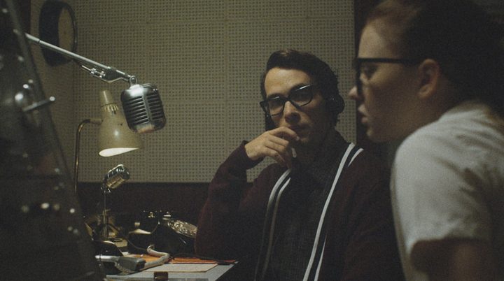 un hombre y una mujer sentados frente a un micrófono