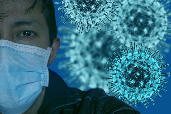Una persona con una masscarilla y una representación del coronavirus