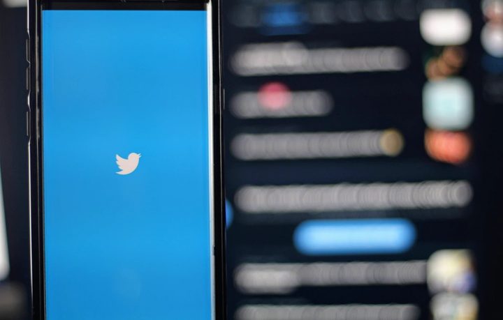 Un celular con la aplicación de Twitter con una computadora de fondo