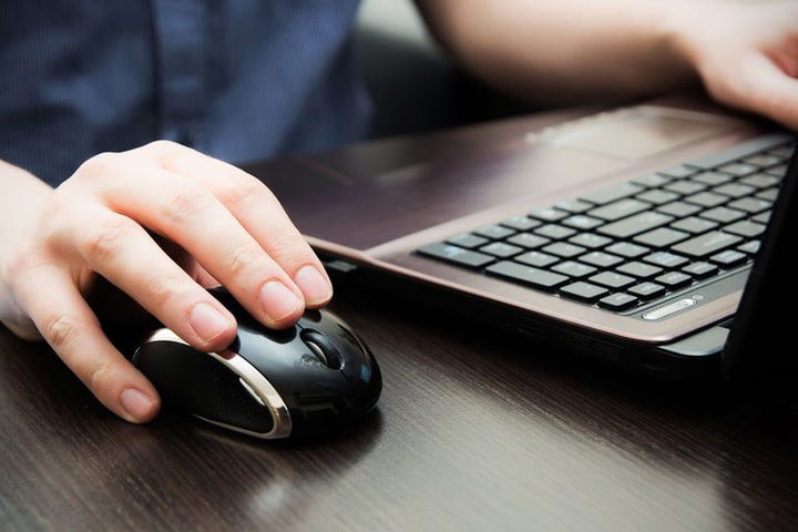 Un hombre usando su laptop con mouse y teclado para aprender cómo desinstalar un programa en Windows 10