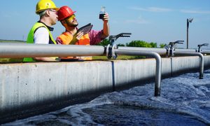 La imagen muestra a dos ingenieros analizando una muestra de aguas residuales.